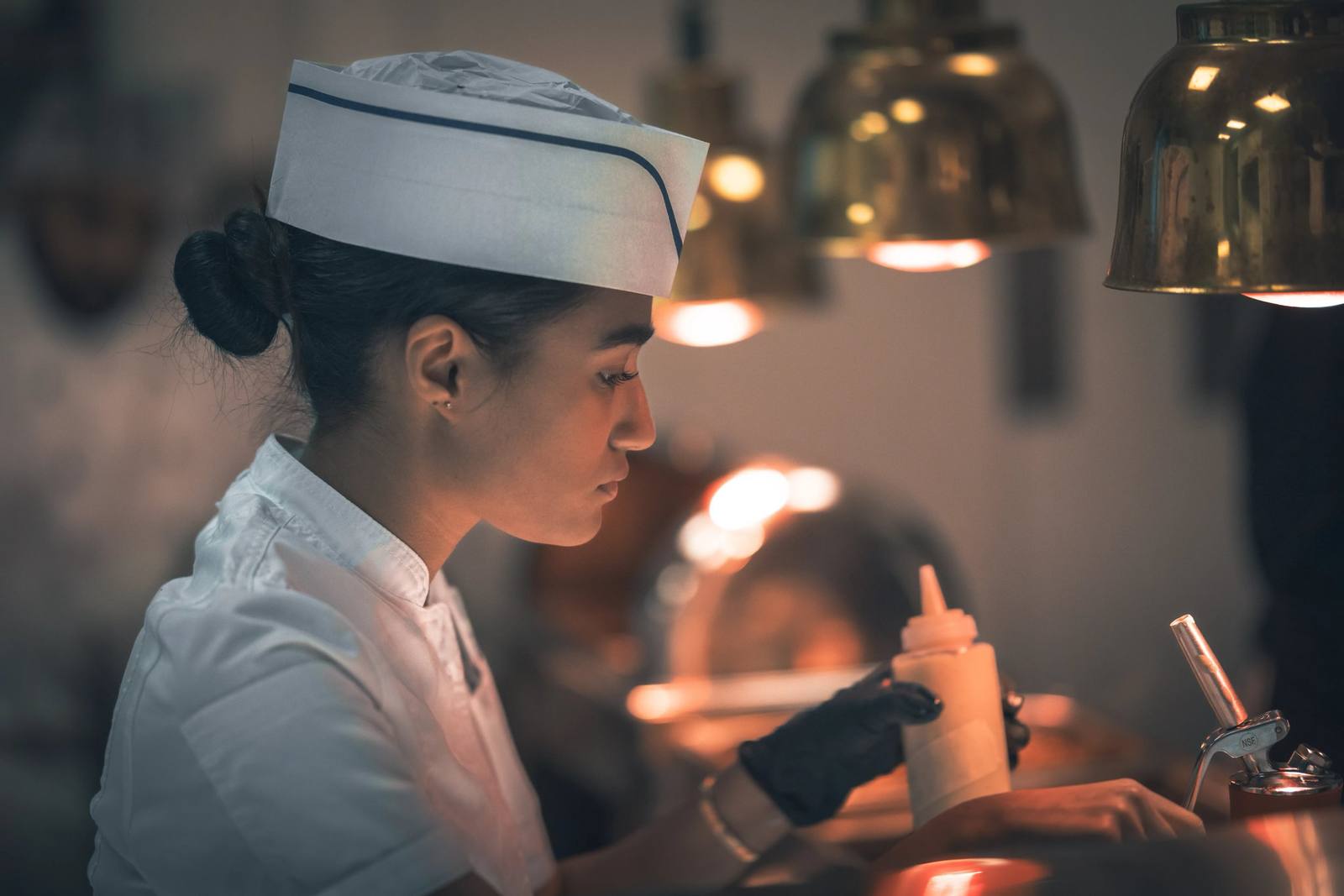 BHMS culinary student plating a fine-dining dish in the teaching kitchen